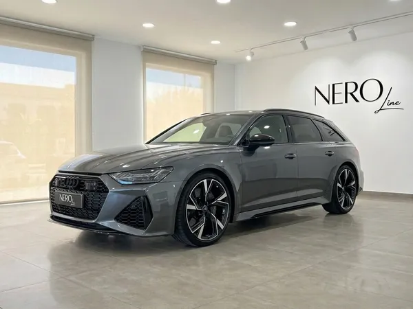 The 2022 Audi RS6 in gloss metallic Daytona Grey Metallic, displayed in a front three-quarter view, parked in a Marbella showroom.