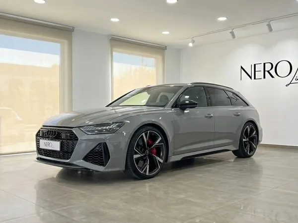 The matte gray Audi RS6 Avant, a luxury supercar, is showcased from a front three-quarter view in a bright Marbella showroom.