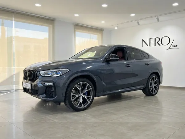 짙은 회색 2020년형 BMW X6 럭셔리 SUV가 알리칸테의 밝은 NEROline 쇼룸에서 전면 쿼터 뷰로 전시되어 있습니다.