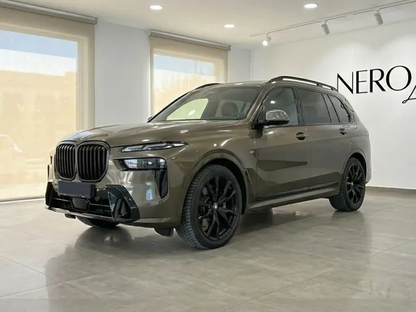 다크 올리브 그린 BMW X7 3.0d 럭셔리 SUV가 알리칸테 실내에 주차된 채 전면 4분의 3 각도에서 보여집니다.