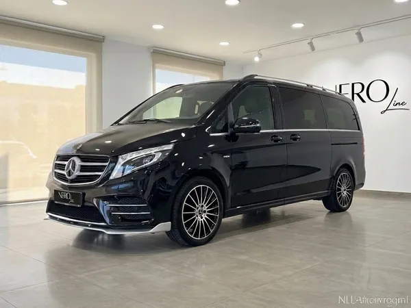 광택 옵시디언 블랙 메르세데스-벤츠 V250d 에르메스 VIP 밴이 바르셀로나 쇼룸에서 전면 쿼터 앵글로 전시되어 있습니다.