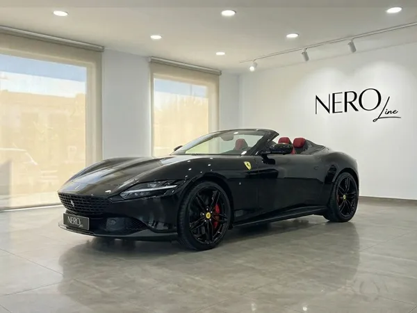 2025年型フェラーリローマスパイダーブラックが、オープンルーフと赤い内装でマドリードのショールームに展示されています。