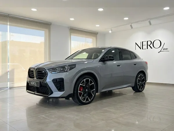 2024년형 BMW X2 M35i xDrive 유광 메탈릭 그레이 차량이 마르베야 쇼룸에서 전면 쿼터 앵글로 전시되어 있습니다.
