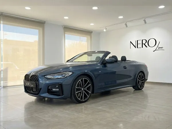 다크 블루 BMW 420 카브리올레가 지붕을 내린 채 전시되어 있으며, 알리칸테 쇼룸에서 세련된 디자인을 선보입니다.