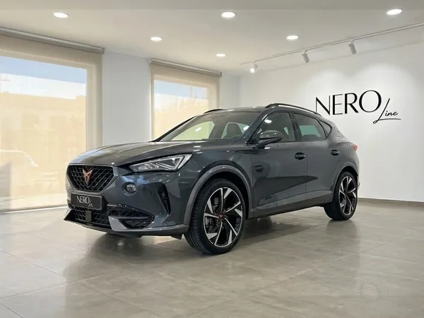 Un SUV Cupra Terramar gris oscuro metalizado brillante se exhibe desde un ángulo frontal de tres cuartos en un luminoso showroom de Alicante.