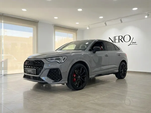 2022년형 아우디 RS Q3 글로스 나르도 그레이가 마르베야 럭셔리 쇼룸에서 전면 쿼터 뷰로 전시되어 있습니다.