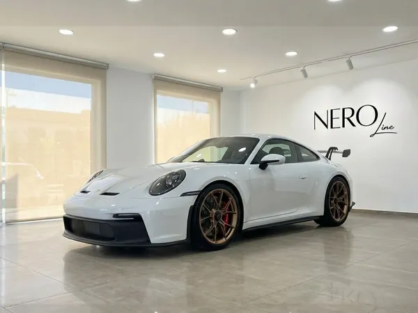 흰색 포르쉐 911 GT3 992가 마르베야 쇼룸에 전시되어 있으며, 인상적인 전면 쿼터 뷰와 브론즈 휠을 특징으로 합니다.