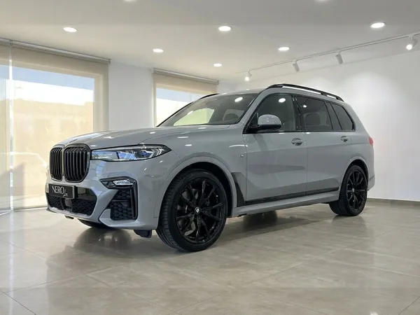 검은색 휠이 장착된 회색 BMW X7 xDrive M Sport가 마르베야 실내에서 전면 쿼터 뷰로 전시되어 있습니다.