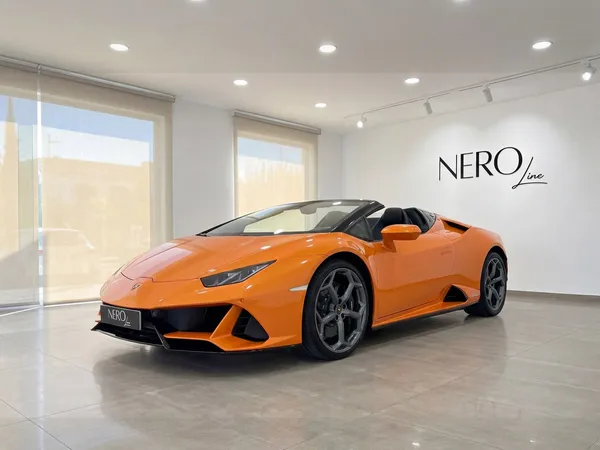 A vibrant orange Lamborghini Huracan Evo Spyder, convertible top down, is showcased in a modern Malaga showroom.