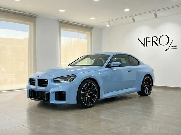 2025년형 라이트 블루 BMW M2 Competition이 알리칸테 쇼룸에 주차되어 있으며, 전면 쿼터 뷰를 보여줍니다.