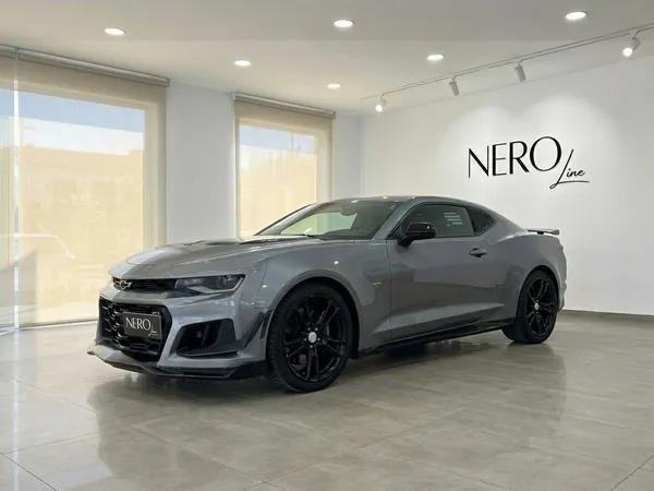 El elegante Chevrolet Camaro 2020 gris se exhibe en una vista tres cuartos frontal dentro de una luminosa sala de exposición en Alicante.