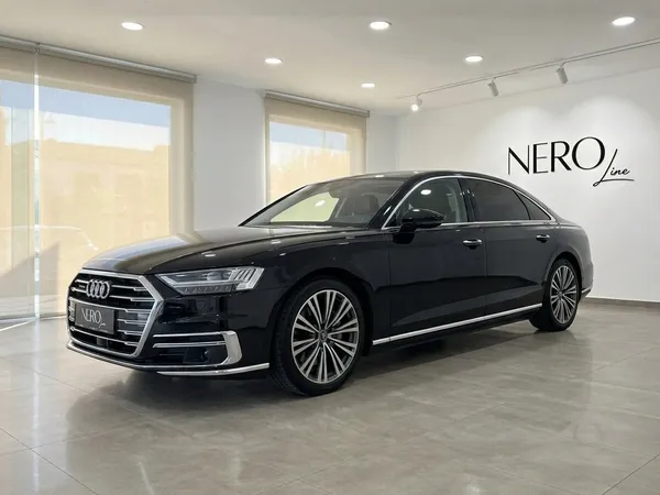 The black 2021 Audi A8 L luxury sedan is showcased from a front three-quarter view in a showroom in Alicante.