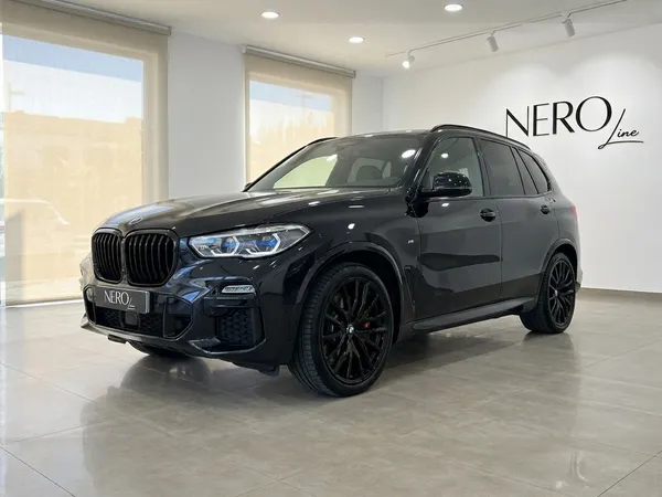 검은색 BMW X5 xDrive M Sport가 마르베야의 현대적인 쇼룸에서 전면 쿼터 앵글로 전시되어 있습니다.