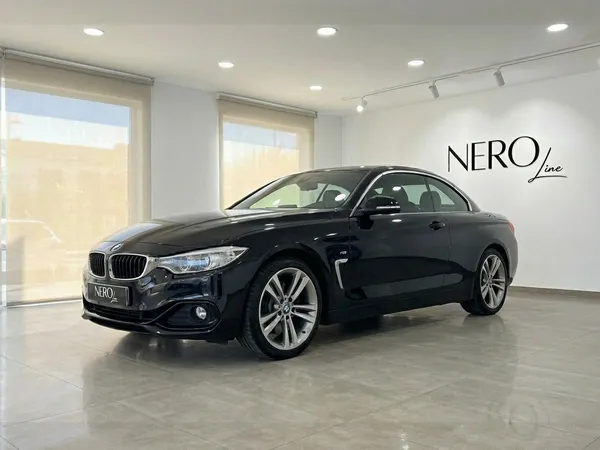하드톱이 닫힌 검은색 BMW 420 카브리올레가 알리칸테의 현대적인 쇼룸에서 전면 쿼터 앵글로 전시되어 있습니다.