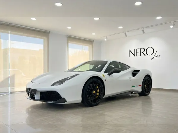 A matte white Ferrari 488 GTB is showcased from a front three-quarter view in a modern showroom with the Nero Line logo in Madrid.