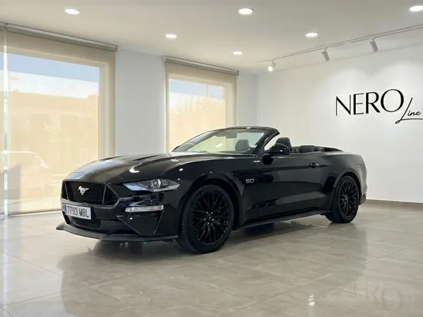 El Ford Mustang GT Convertible negro con la capota bajada se exhibe en un moderno concesionario en Barcelona.