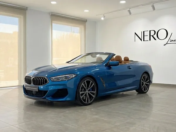 알리칸테 쇼룸에 스카이 블루 BMW M850i 카본 코어 에디션 컨버터블이 오픈탑과 탄색 인테리어로 전시되어 있습니다.