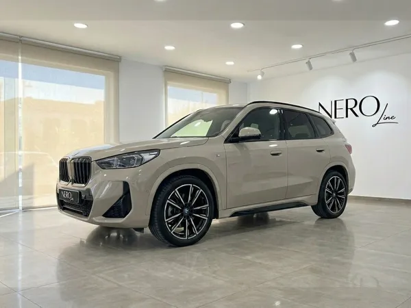 광택 베이지색 BMW X3 2.0 디젤이 알리칸테의 현대적인 쇼룸 내부에서 전면 쿼터 앵글로 전시되어 있습니다.