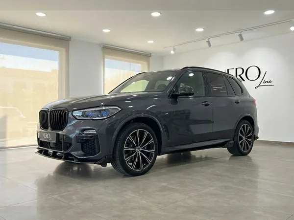짙은 회색 BMW X5 xDrive45e가 알리칸테 실내에 주차된 채 전면 4분의 3 각도에서 전시되어 있습니다.