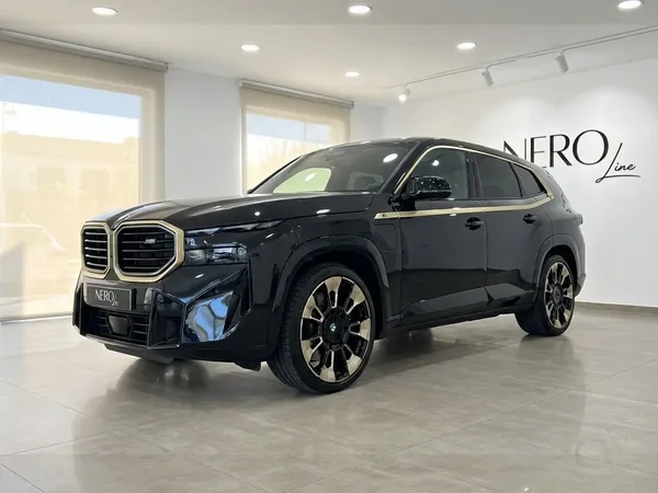 검은색 2025년형 BMW XM 퍼포먼스 SUV가 알리칸테의 쇼룸에서 전면 쿼터 뷰로 전시되어 있습니다.