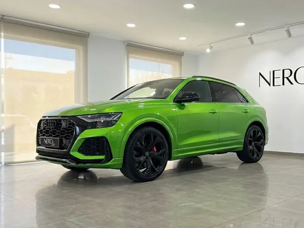 The neon green Audi RS Q8, a luxury performance SUV, is prominently displayed from a front three-quarter angle in a modern showroom in Madrid.