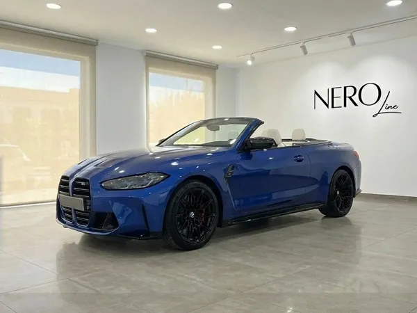 El BMW M4 Competition Convertible 2025 azul metálico, con la capota bajada y el interior blanco, se exhibe en un concesionario de Barcelona.