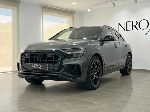 The matte gray Audi Q8 TDI is showcased in a showroom, captured from a front three-quarter view in Alicante.