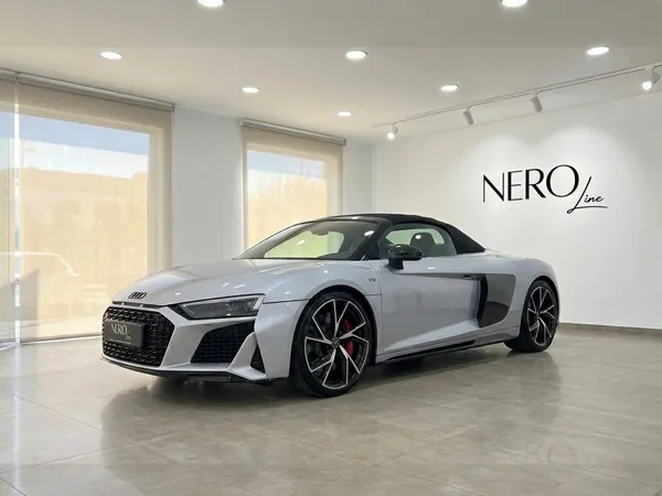 은색 2021년형 아우디 R8 스파이더 퍼포먼스 컨버터블이 이비자 밝은 전시장에서 전면 쿼터 앵글로 전시되어 있습니다.