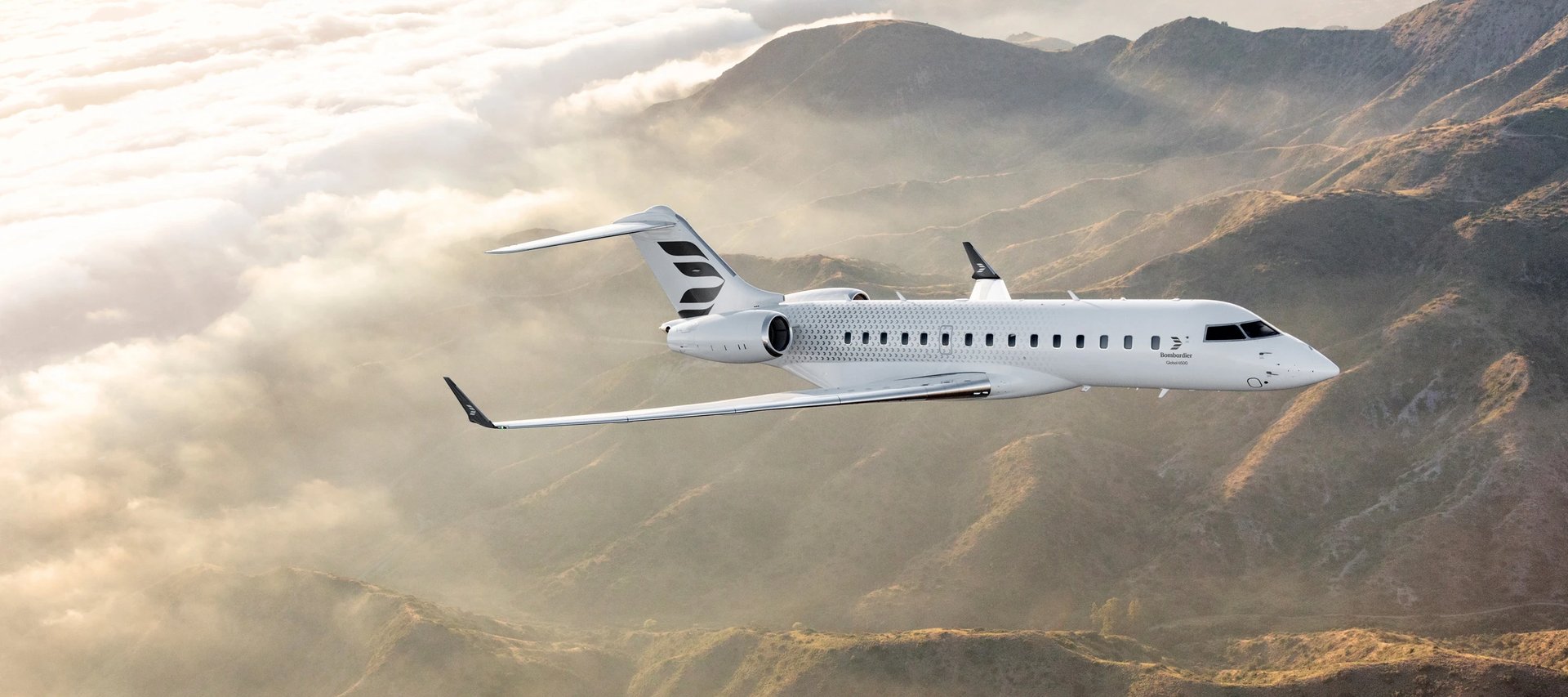 The sleek Bombardier Global 6500 private jet flies gracefully above misty mountains near Madrid, showcasing its elegant design.