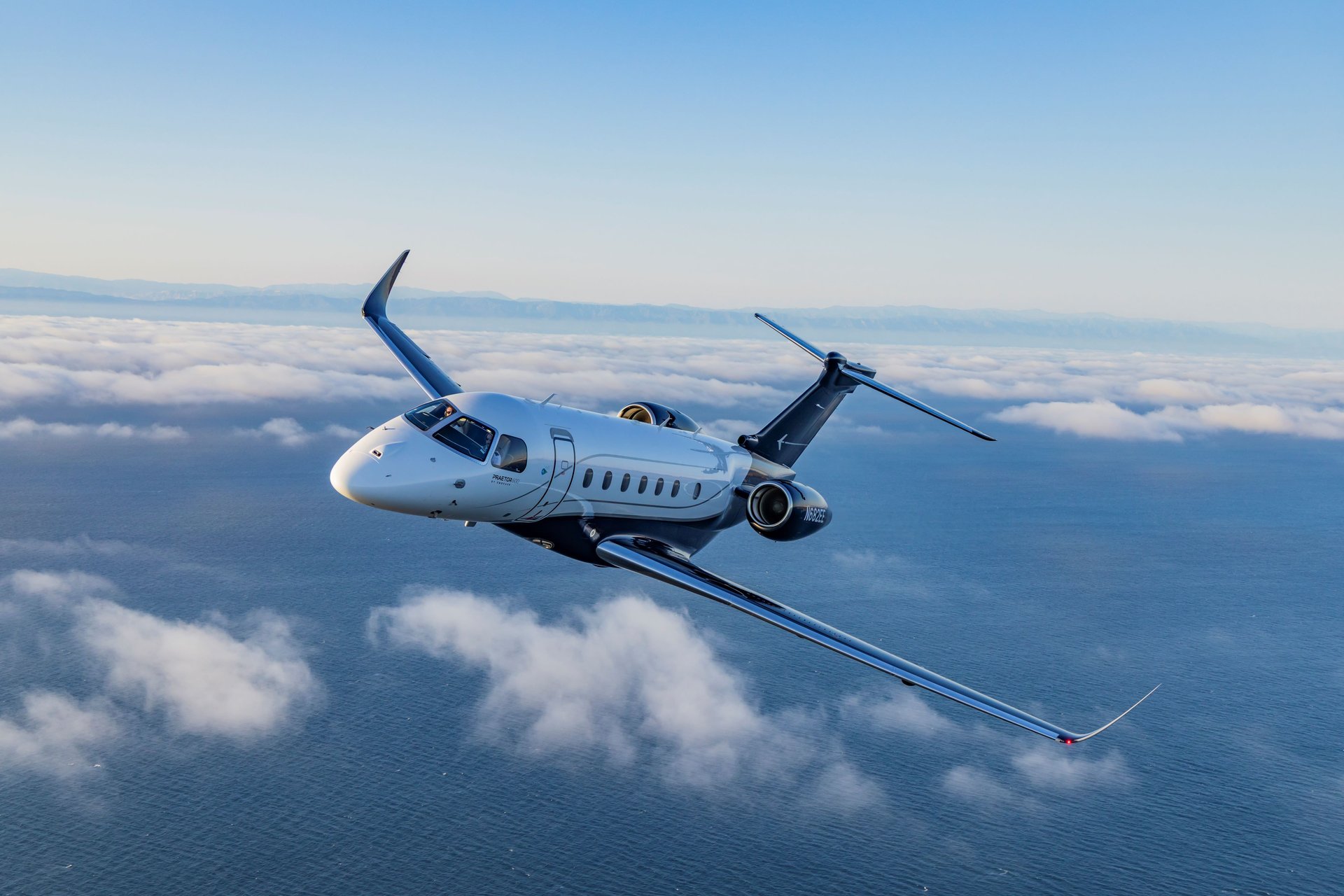 Embraer Legacy 500 — Flying above the ocean The Embraer Legacy 500 private jet flies gracefully above the clouds and ocean, showcasing its sleek design.