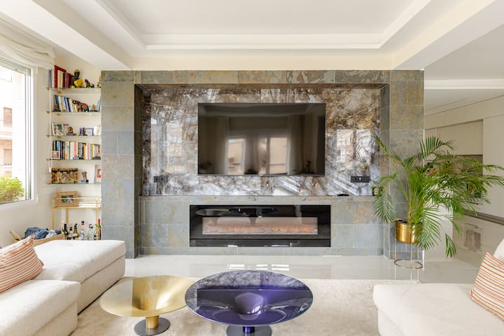 Bernabeus Beauty — Wohnzimmer mit TV und Kamin Die Villa Bernabeus Beauty in Madrid bietet ein modernes Wohnzimmer mit großem Fernseher, stilvollem Kamin und bequemen Sofas.