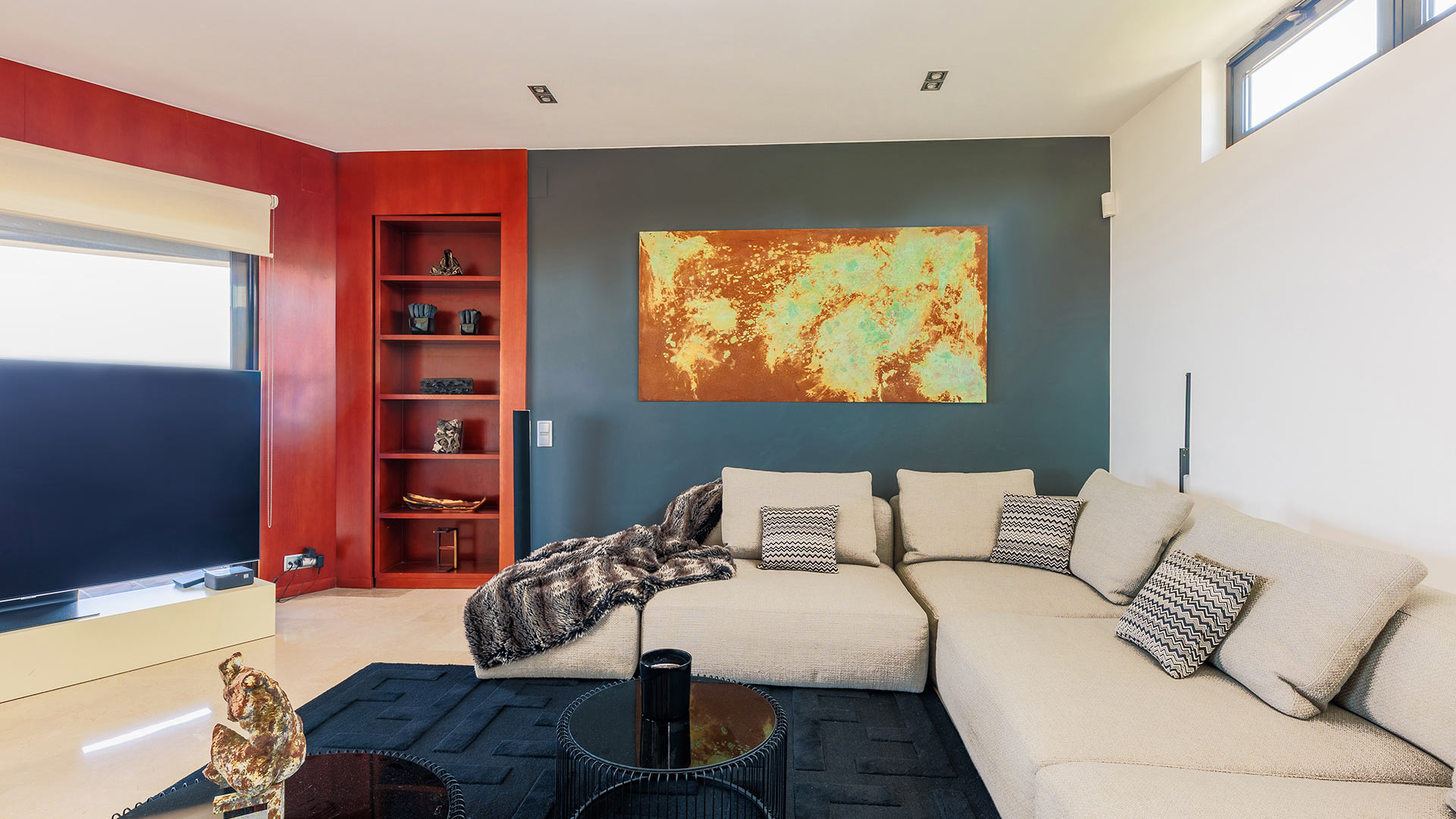 Villa Imelda — Modernes Wohnzimmer Das moderne Wohnzimmer der Villa Imelda in Barcelona zeigt ein großes Ecksofa, abstrakte Kunst und ein rotes Regal.