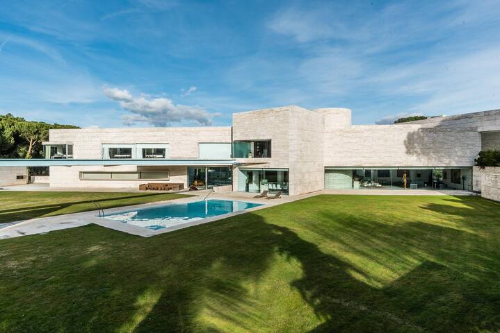 Das moderne Äußere der Villa Ophelia zeigt ein elegantes Design, eine weitläufige grüne Rasenfläche und einen einladenden Pool in Madrid.