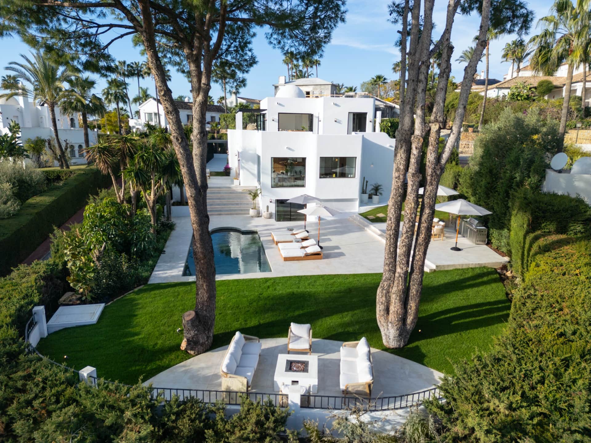 Villa Sherin — Modernes Wohnzimmer, Marbella Das elegante Wohnzimmer der Villa Sherin in Marbella bietet plüschige weiße Sofas, eine stilvolle Holzlamellenwand und eine moderne Treppe.