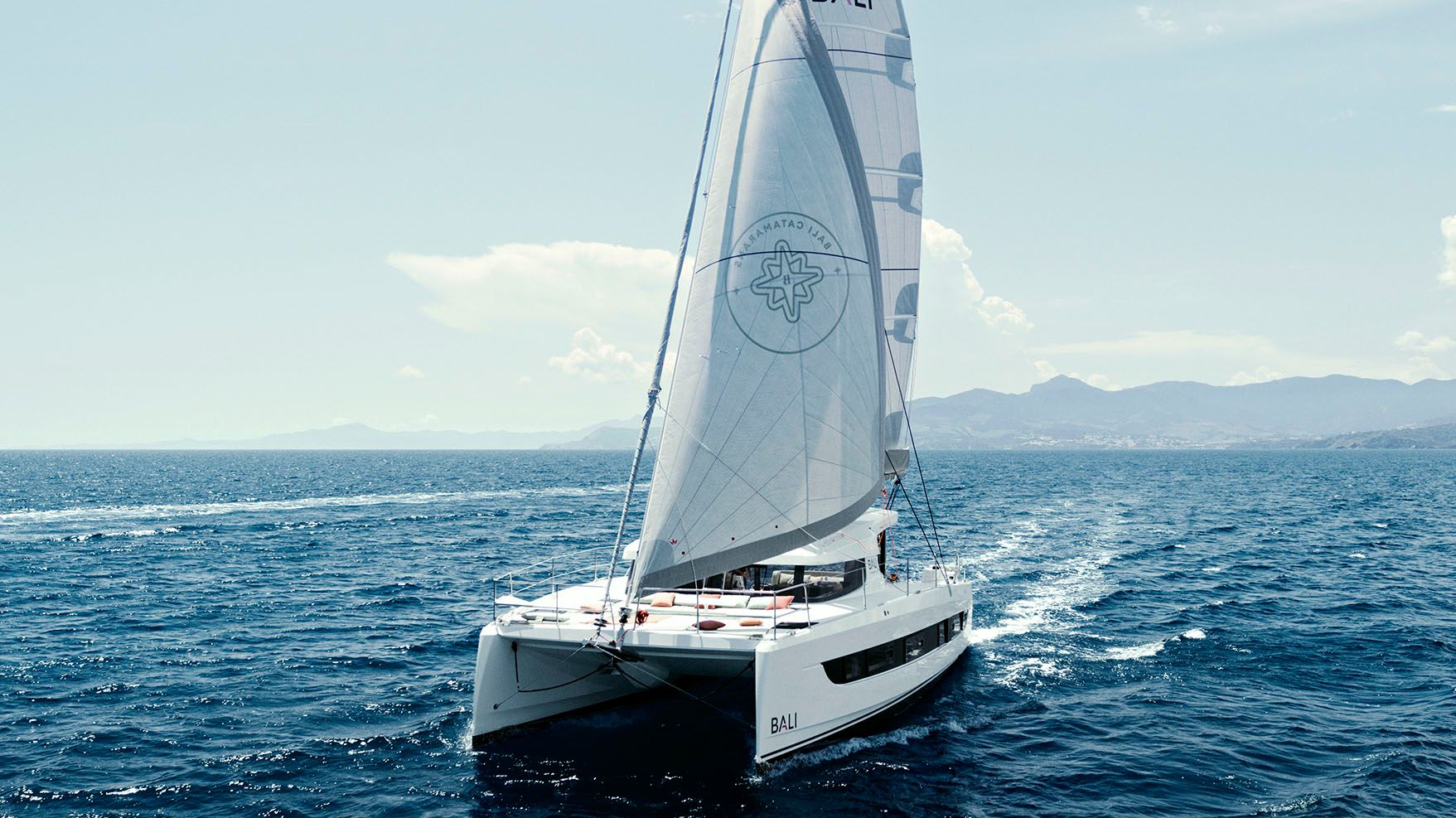 Bali Catsmart Katamaran segelt auf blauem Wasser nahe Ibiza, zeigt sein volles Segel und die Buglounge.