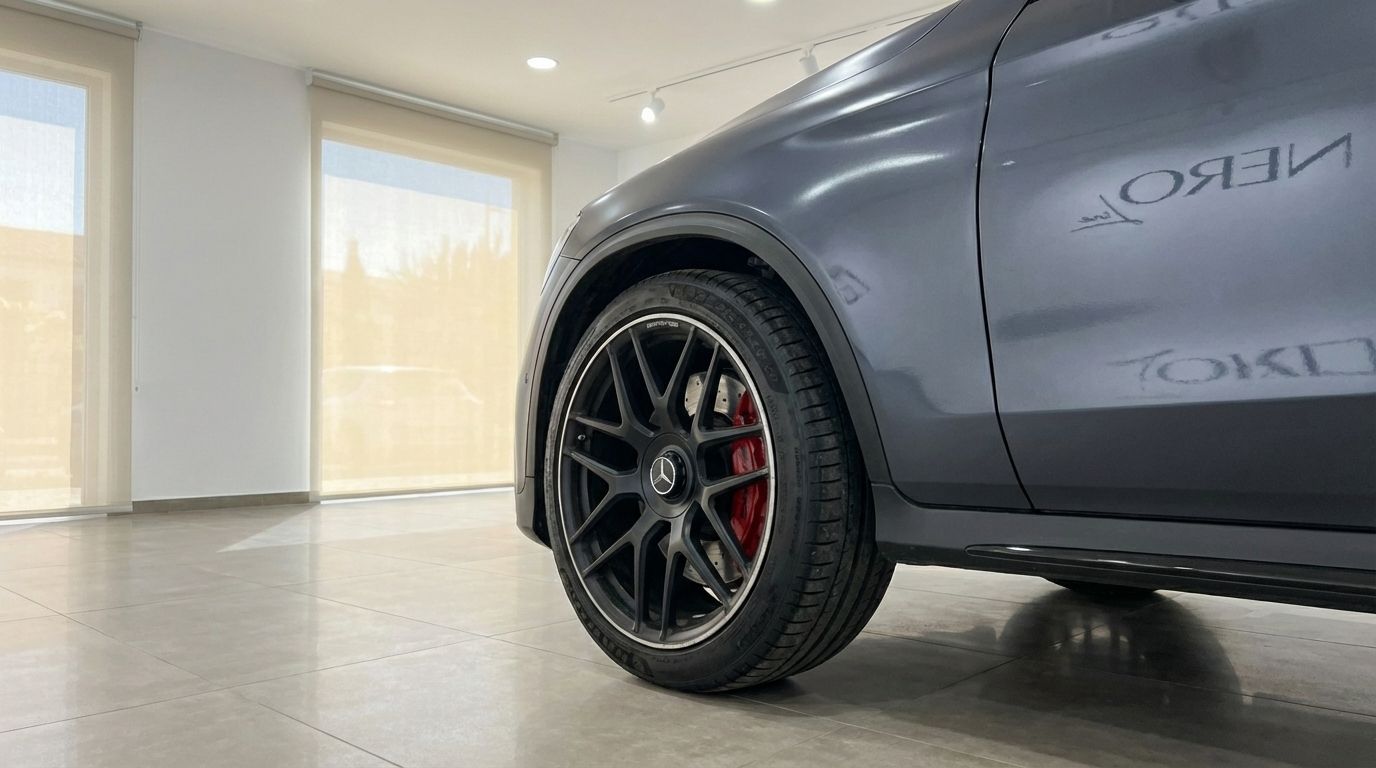 The metallic gray Mercedes-Benz GLC 63 S AMG in Alicante showcases its black multi-spoke front wheel with red brake calipers.