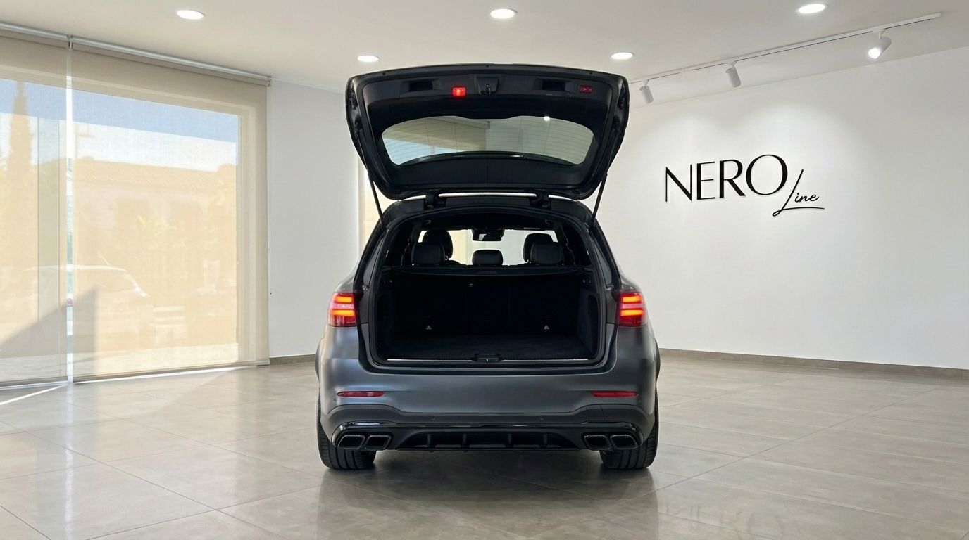 The metallic gray Mercedes-Benz GLC 63 S AMG is shown from the rear with its trunk open, parked in a showroom in Alicante.
