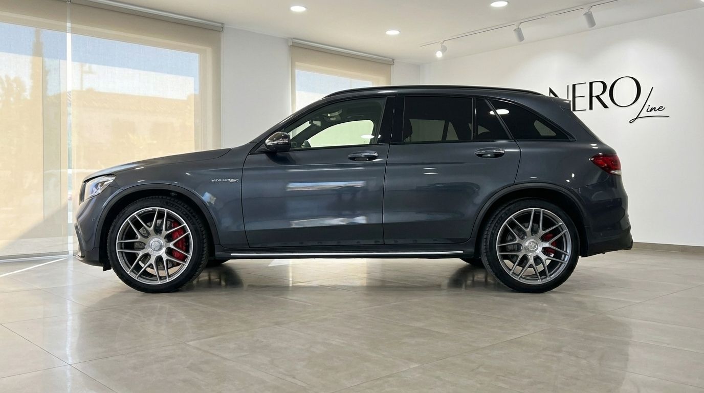 The metallic gray Mercedes-Benz GLC 63 S AMG is shown in a side profile view within a brightly lit showroom in Alicante.
