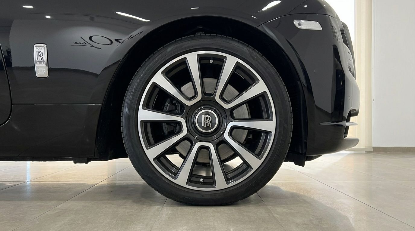 The Rolls-Royce Wraith's front wheel and fender, showcasing its elegant multi-spoke alloy rim and jet black paintwork in Malaga.