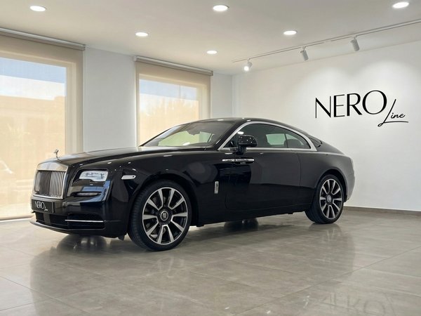Rolls-Royce Wraith — Side view in Malaga showroom The black 2024 Rolls-Royce Wraith luxury coupe is showcased from a side view in a modern showroom in Malaga.