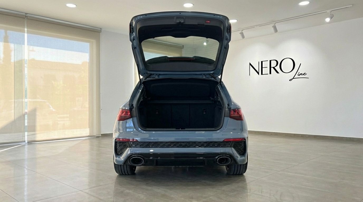 The rear view of a blue-gray Audi RS3 with its trunk open, parked in a showroom in Alicante.