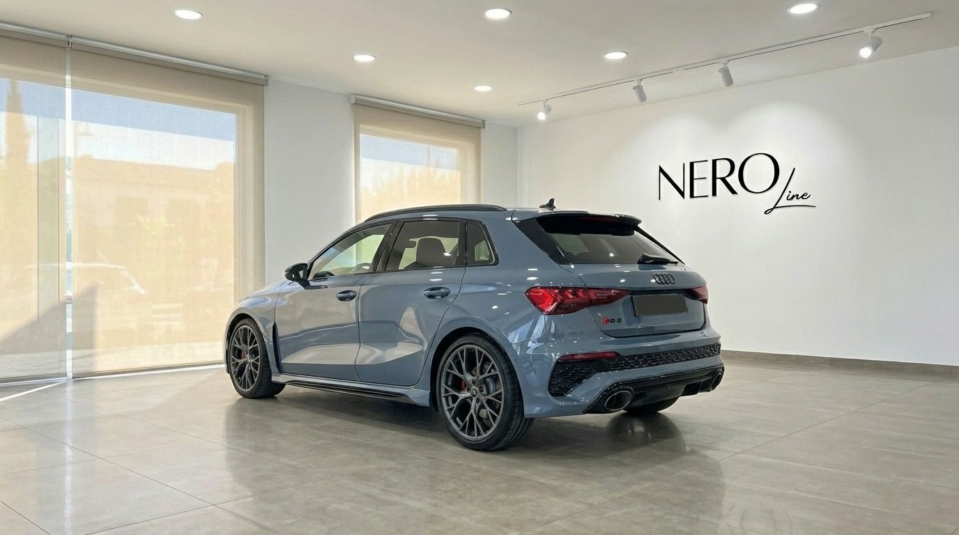 A blue-gray Audi RS3 is parked indoors, showcasing its sleek rear three-quarter view in Alicante.