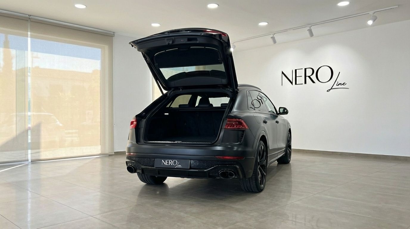 The matte black Audi SQ8 RS Body is shown from the rear with its trunk open, revealing ample cargo space in Alicante.