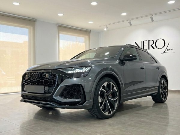 Audi RS Q8 — Front three-quarter view in Alicante The metallic gray Audi RS Q8 performance SUV is showcased from a front three-quarter view in a bright showroom in Alicante.
