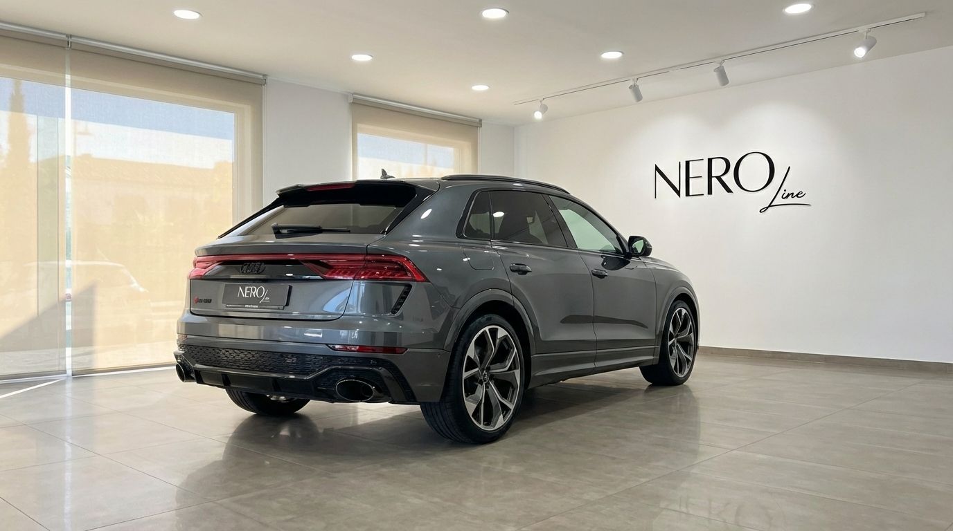 The metallic gray Audi RS Q8 performance SUV is parked in a bright showroom, viewed from the rear three-quarter angle in Alicante.