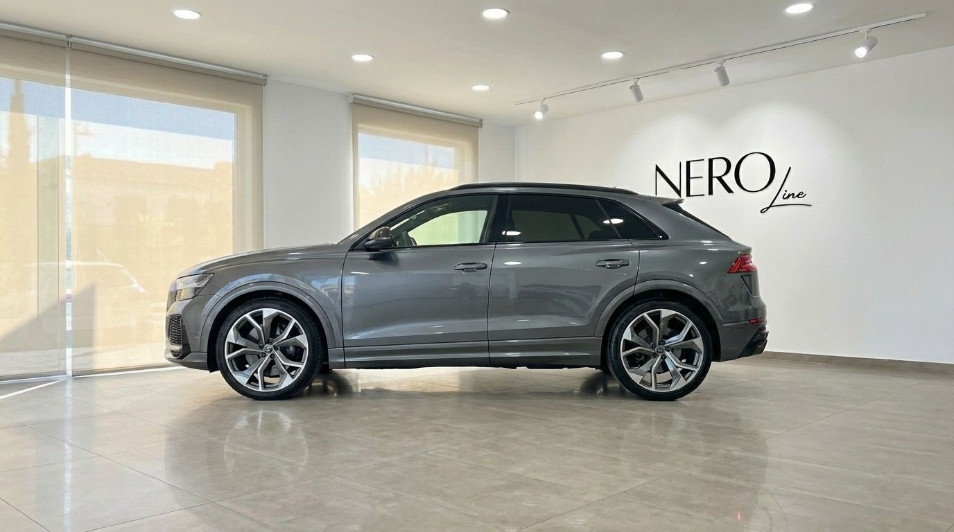 The metallic gray 2024 Audi RS Q8 performance SUV is showcased in a showroom with large windows in Alicante.
