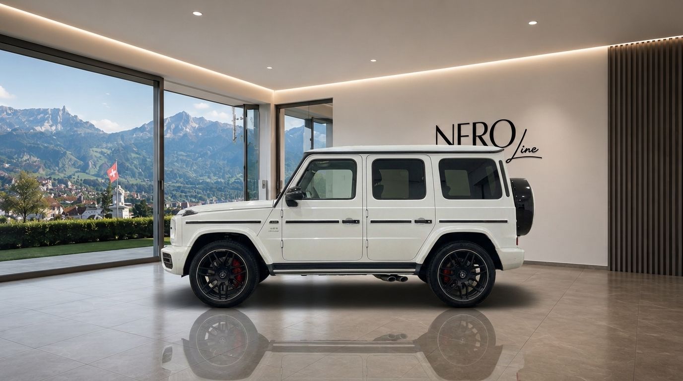 The white Mercedes G63 – Weiss is displayed in a modern Zurich showroom, showcasing its side profile against a stunning mountain backdrop.