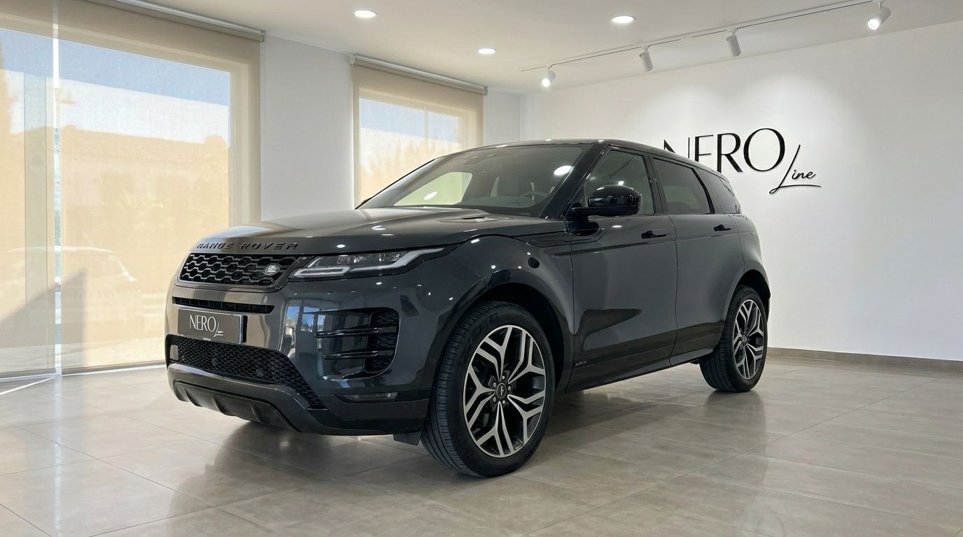 A dark grey Land Rover Range Rover Evoque R-Dynamic (1st) is showcased from a front three-quarter angle inside a modern showroom in Alicante.