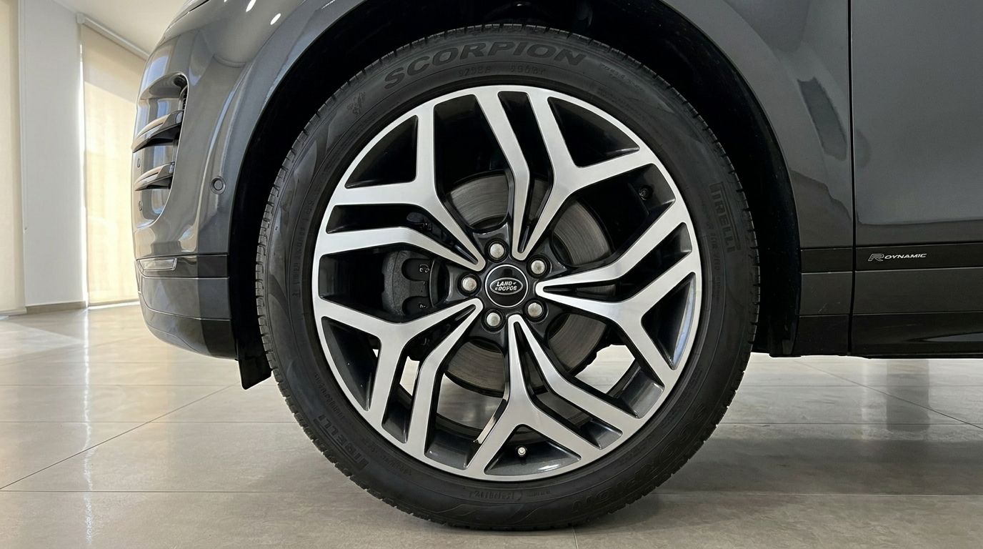The Land Rover Range Rover Evoque R-Dynamic in metallic black features a detailed view of its distinctive two-tone front wheel and tire in Alicante.