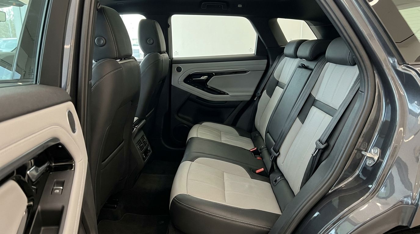 The Land Rover Range Rover Evoque R-Dynamic (1st) in Alicante features a luxurious rear interior with two-tone leather seats and a detailed door panel.